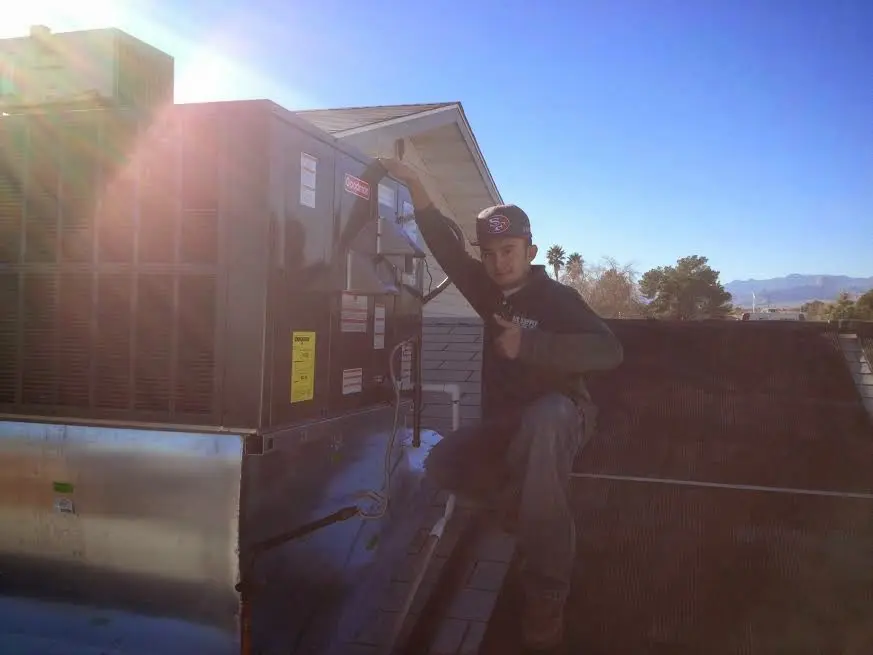 HVAC technician performing Air Duct Cleaning on a rooftop unit in DeRidder